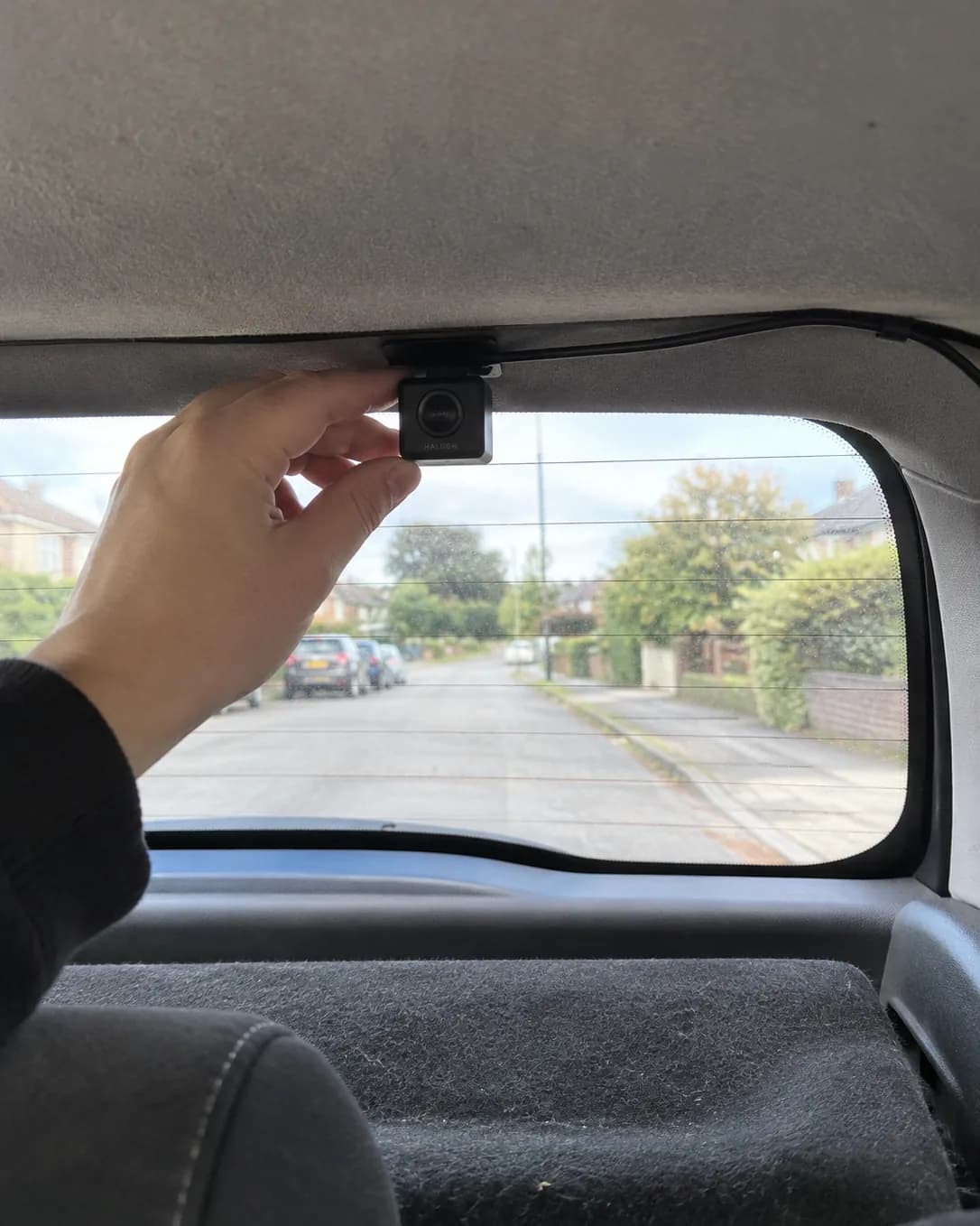 The small Halden rear camera stuck inside the top of a hatchback rear window, its cable tucked into the roof lining